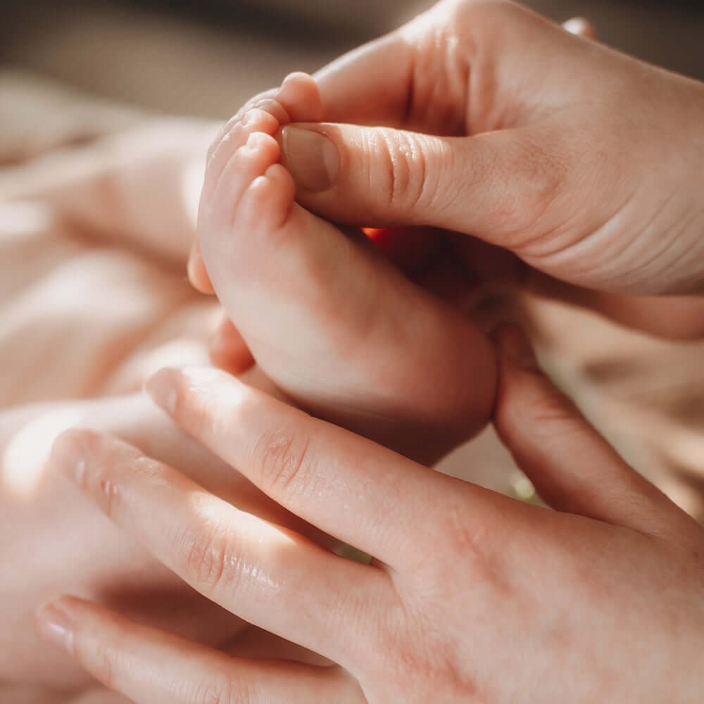 baybies Baby wird mit Baby Öl an den Füßchen eingecremt