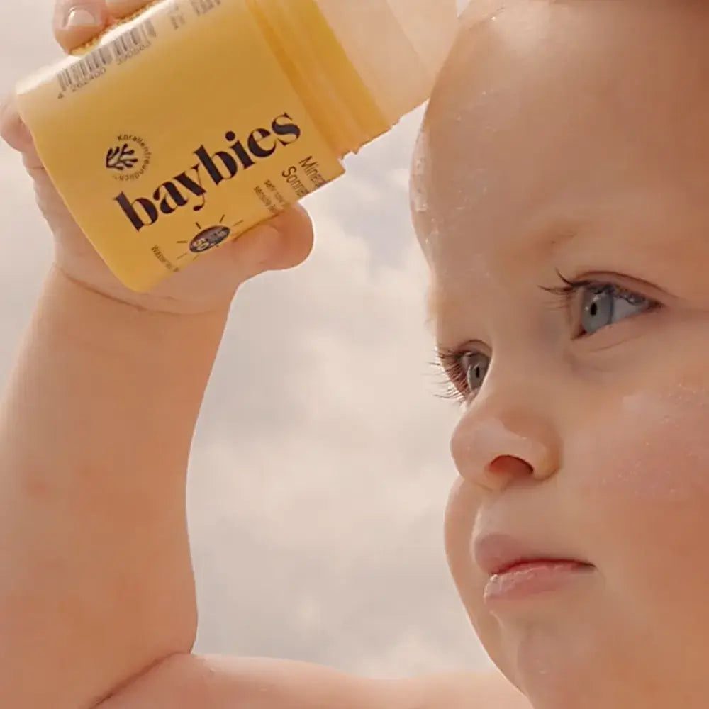 baybies Baby cremt sich das Gesicht mit Mineralischen Sonnen Roll-On LSF50+ ein