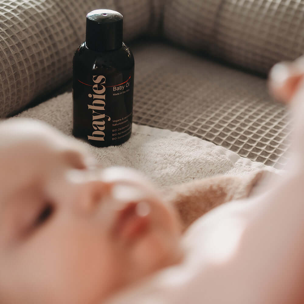 baybies Baby im Vordergrund mit Baby Öl dahinter 